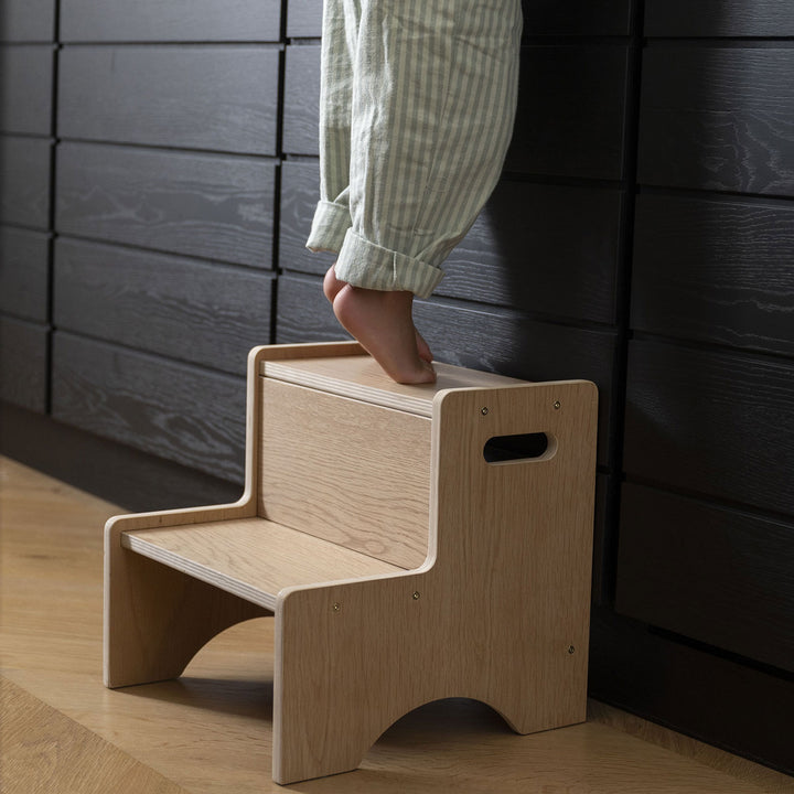 Copil mic urcând pe treaptă Montessori din lemn natural
